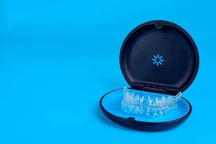Clear aligners stored in a black travel case on blue background – Invisalign® orthodontic treatment