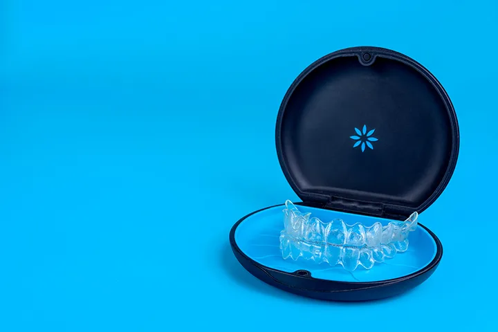 Clear aligners stored in a black travel case on blue background – Invisalign® orthodontic treatment